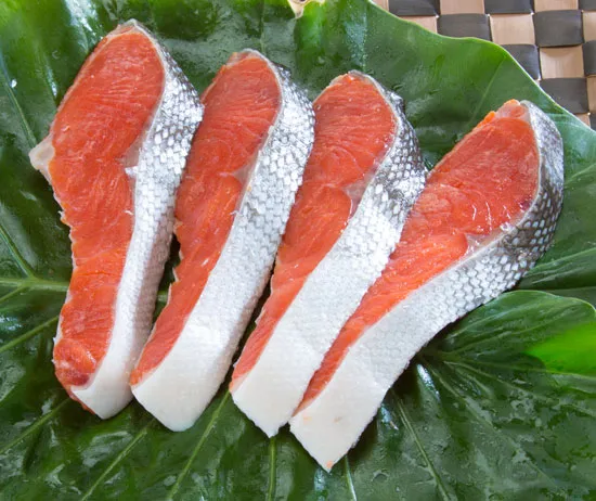 塩紅さけ（中辛：4切れ）の商品写真。脂の乗ったおいしそうな鮭の切り身が４枚かごの上に並んでいる写真。